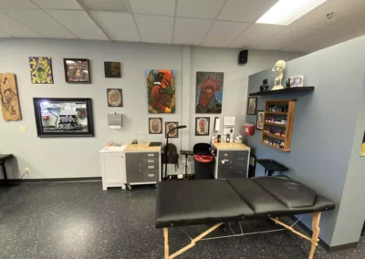 Black portable massage table with tools and paintings, wide shot
