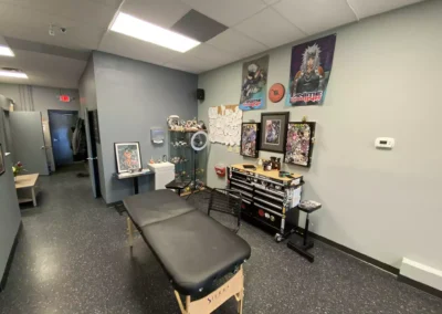Exit door and black portable massage table with anime portrait on the wall, toys, and tools